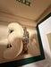 A Rolex watch displayed inside an open cream-colored Rolex presentation box with a cream cushion. The watch has a silver-toned metal case and a gold-toned bracelet.